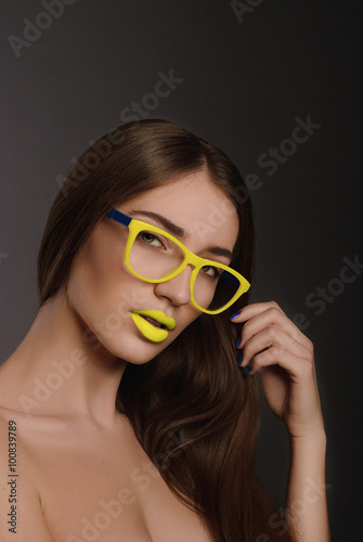 Beauty woman face portrait with yellow lips in yellow sunglasses 