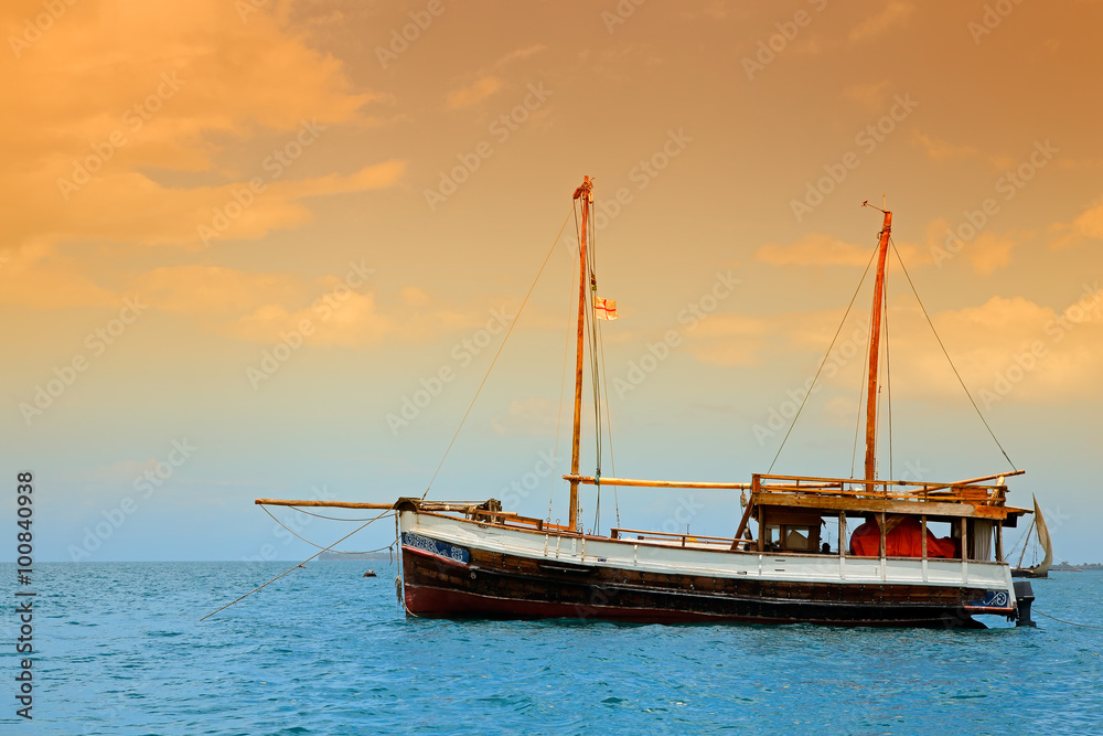Wooden boat floating on the clear turquoise water of Zanzibar island.