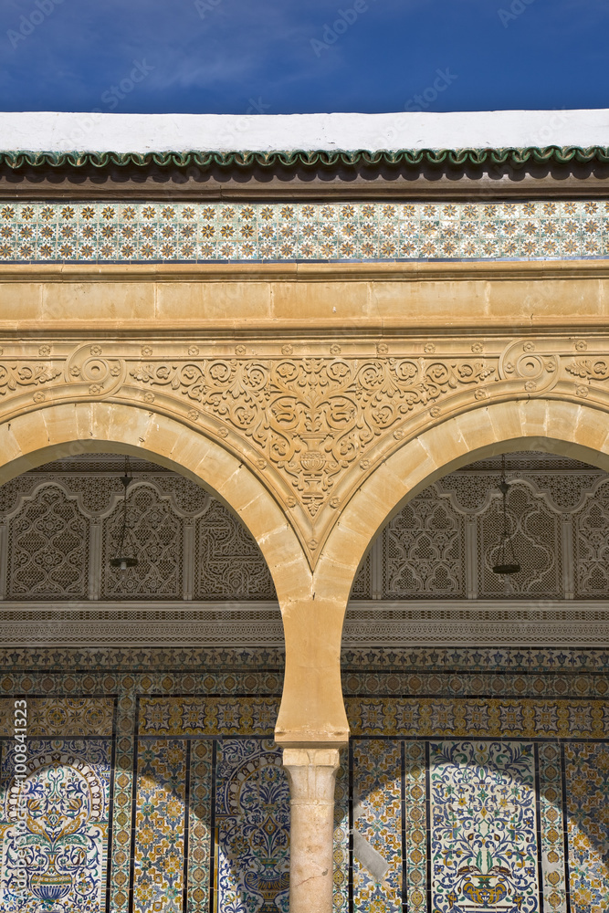 Tunisia. Kairouan - the Zaouia of Sidi Saheb. Fragment of courtyard with decorative arches and wal covered ornamental tiles