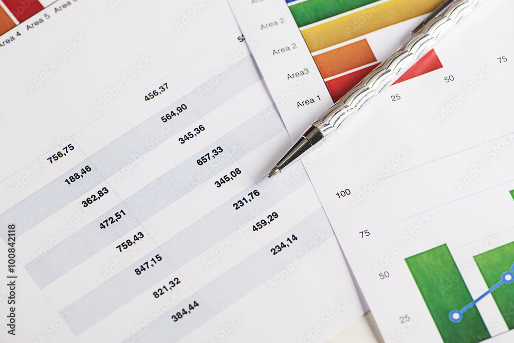 Several colorful charts and numbers on economics and business with a pen Several colorful charts and numbers on economics and business with a pen