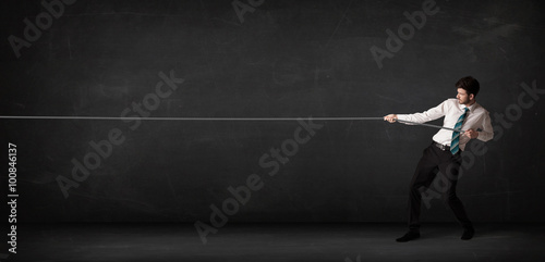 Businessman pulling rope on grey background