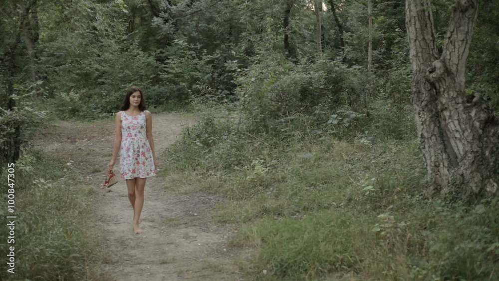 Beautiful girl in the dress walking along a path in the woods Beautiful girl in the dress walking along a path in the woods