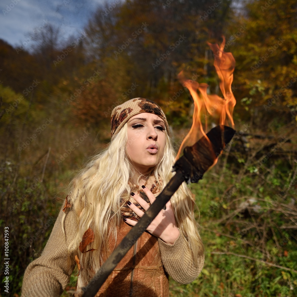 Beautiful young woman outdoor on autumn day holding burning torc