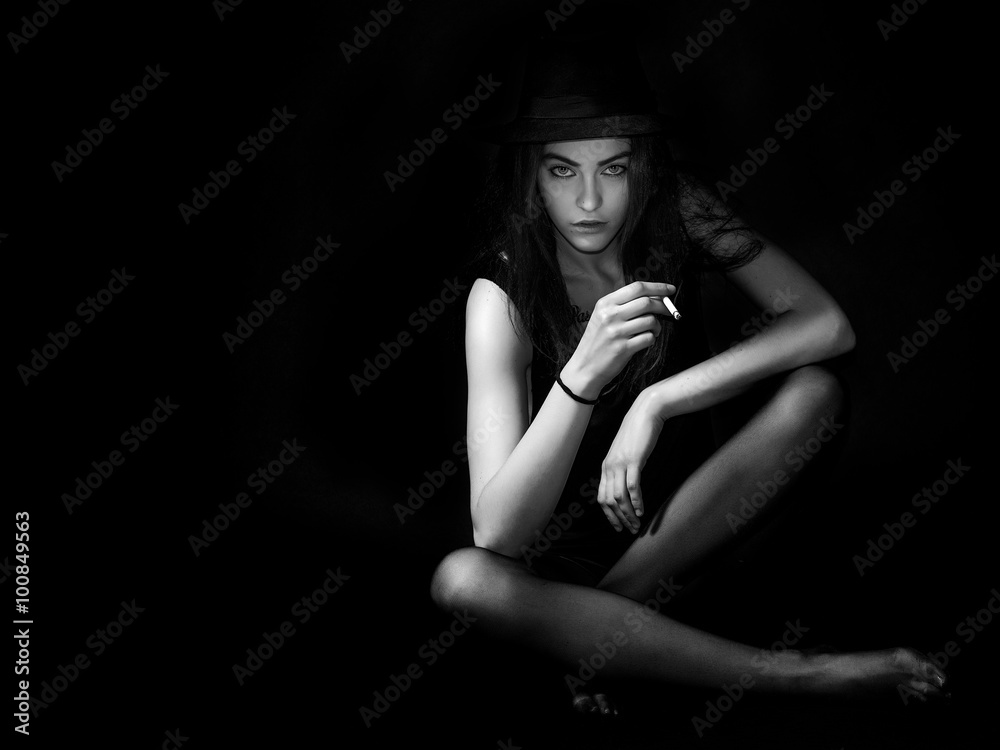 Transgressive girl portrait sitting and smoking cigarette black and white
