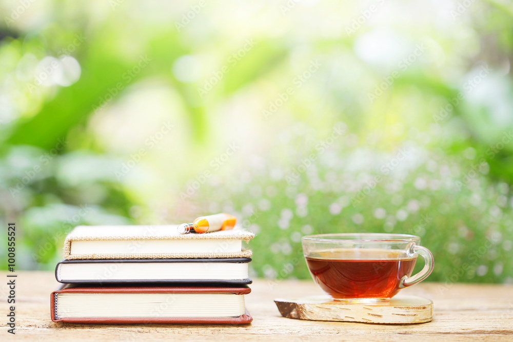 tea in glass and notebook with pens on wooden table at outside tea in glass and notebook with pens on wooden table at outside