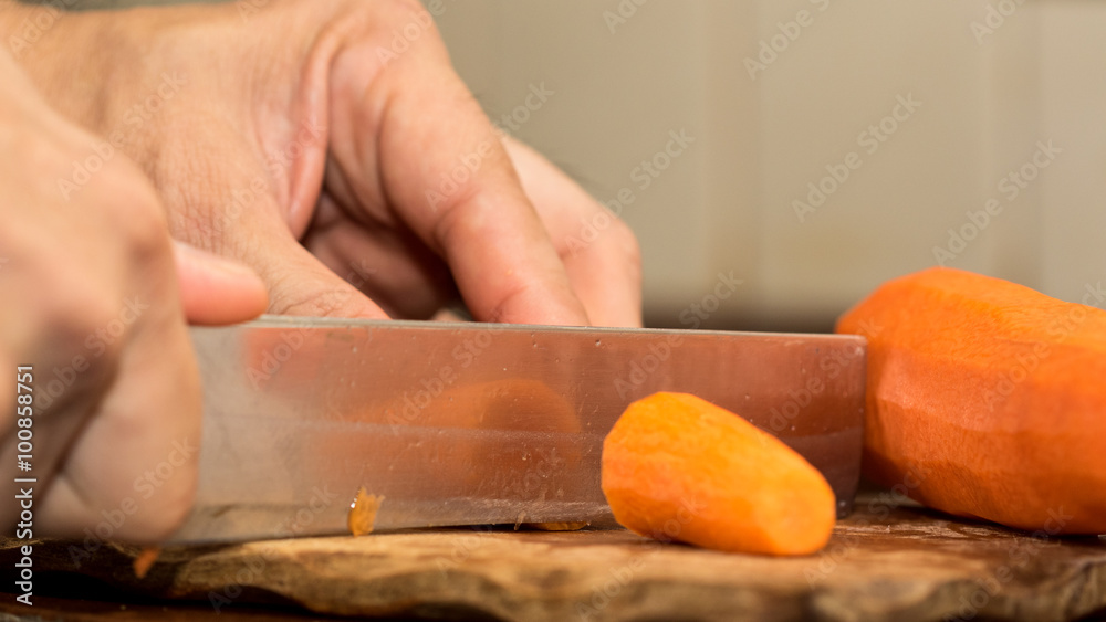 Chef peeling carrot with Knife.