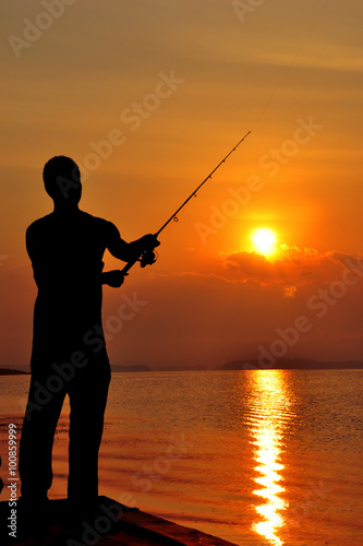Silhouette Man fishing on a lake at sunset