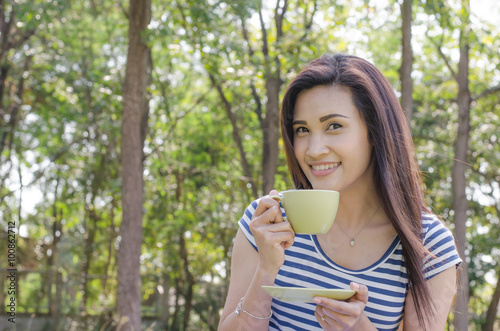 Beautiful Asian woman drinking coffee in park