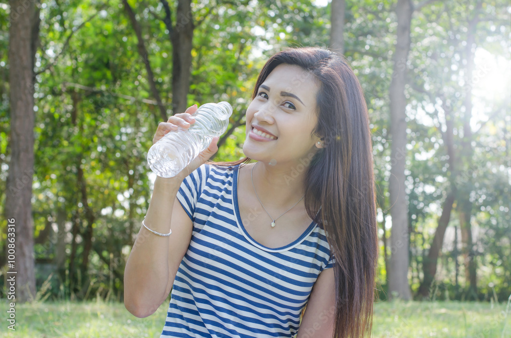 Beautiful Asian woman holding a bottle of water in park Beautiful Asian woman holding a bottle of water in park
