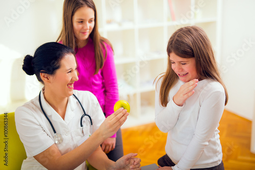 Female doctor nutritionist and patient teenagers.Doctor holding an apple. 