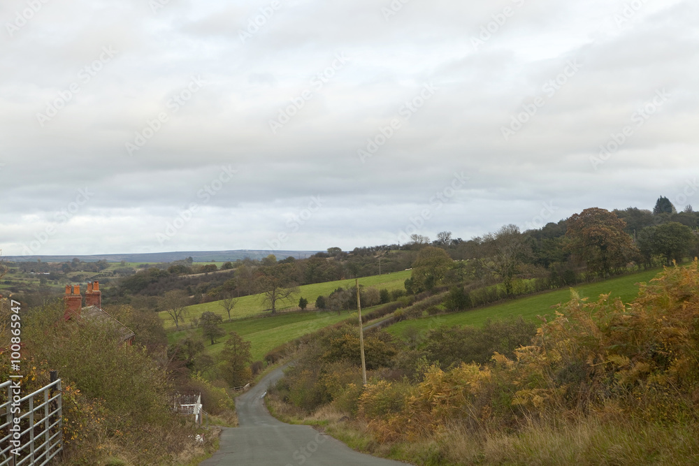 Peaceful Countryside. A narrow country road runs down the valley and up the other side passing through a gentle green rural landscape. Peaceful Countryside. A narrow country road runs down the valley and up the other side passing through a gentle green rural landscape.