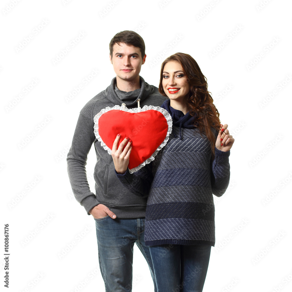 Ordinary beautiful couple having fun with a pillow in the form of heart on Valentine's Day. On a white background. Ordinary beautiful couple having fun with a pillow in the form of heart on Valentine's Day. On a white background.