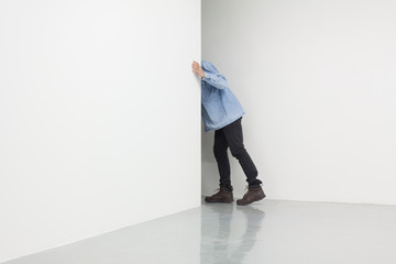 Man in white room looking behind corner