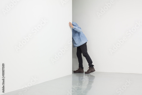 Man in white room looking behind corner