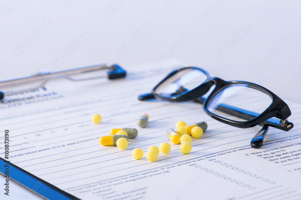 Pills and glasses on top of hospital form. Pills and glasses on top of hospital form.