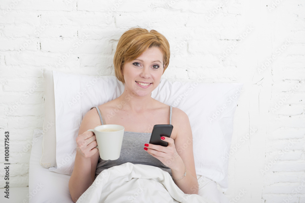 having coffe breakfast on bed while watching internet news in his mobile phone in online communication having coffe breakfast on bed while watching internet news in his mobile phone in online communication