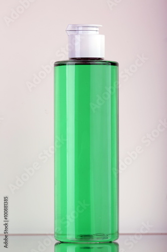 Flacone in plastica trasparente con liquido verde e spruzzatore cromato photo