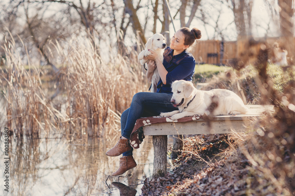 Fototapeta premium Beautiful girl with pets near the lake