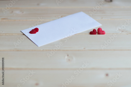 two hearts from sugar lie on wooden pastel-colored background next to the envelope 