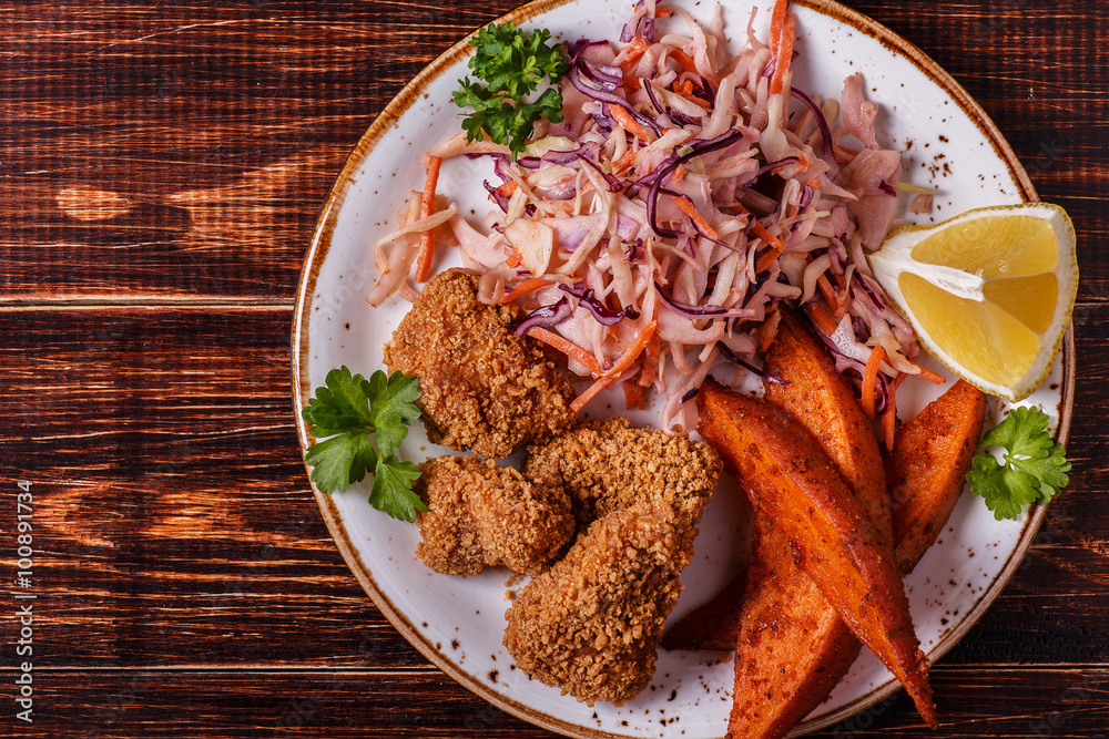 Homemade cooked сhicken nuggets, sweet potatoes and coleslaw. Homemade cooked сhicken nuggets, sweet potatoes and coleslaw.