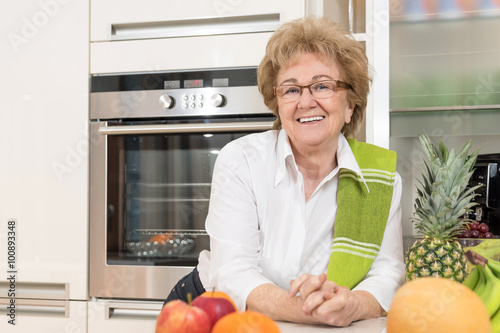 Fényképezés Fröhliche Hausfrau mit frischem Obst in ihrer Küche