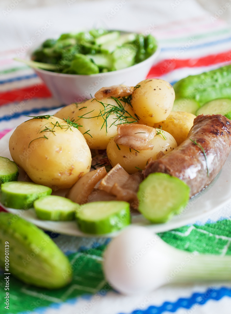 Boiled potatoes with grilled sausage and cucumber