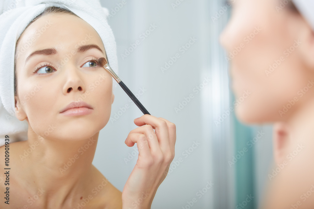 A picture of a young woman applying face powder in the bathroom A picture of a young woman applying face powder in the bathroom
