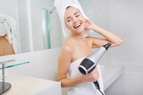 Woman in the bathroom with hairdryer in hand