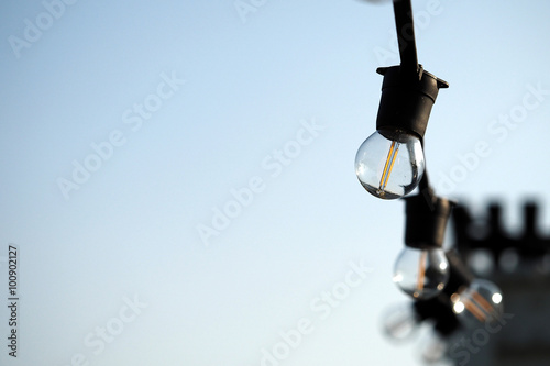 Light bulbs hanging on a electricity wire in clear blue sky background