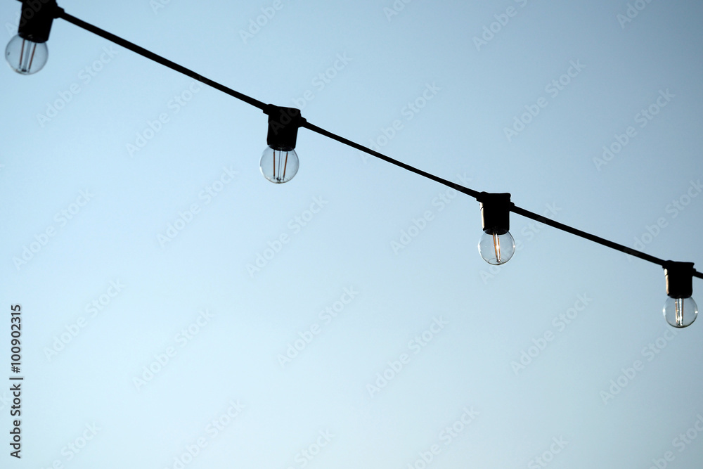 Light bulbs hanging on a electricity wire in clear blue sky background Light bulbs hanging on a electricity wire in clear blue sky background
