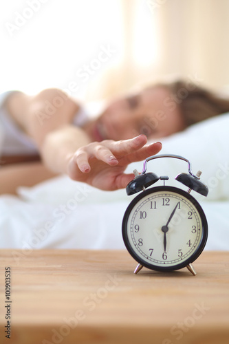 Young sleeping woman and alarm clock in bedroom at home