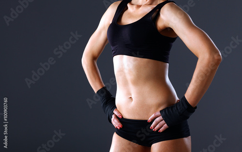 Muscular young woman  standing on gray background © lenets_tan