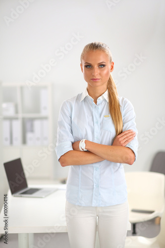 Attractive young businesswoman standing near desk in the office