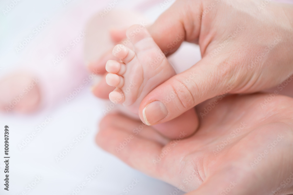Caring mother holding foot of her infant Caring mother holding foot of her infant