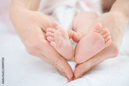 Nursing mother holding keeping legs of her infant © zinkevych