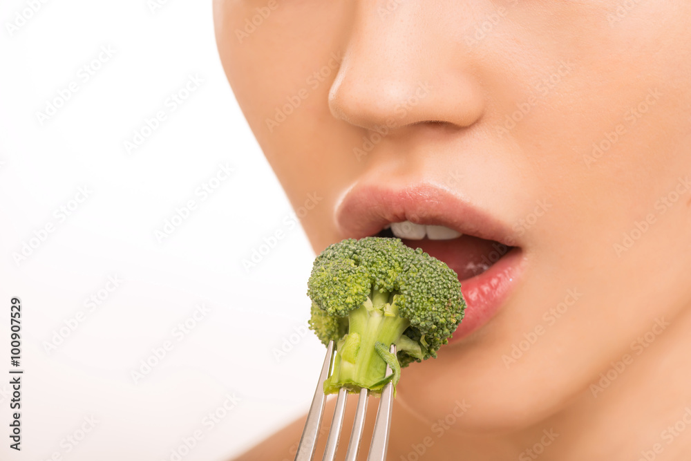 Young girl tasting a broccoli. 