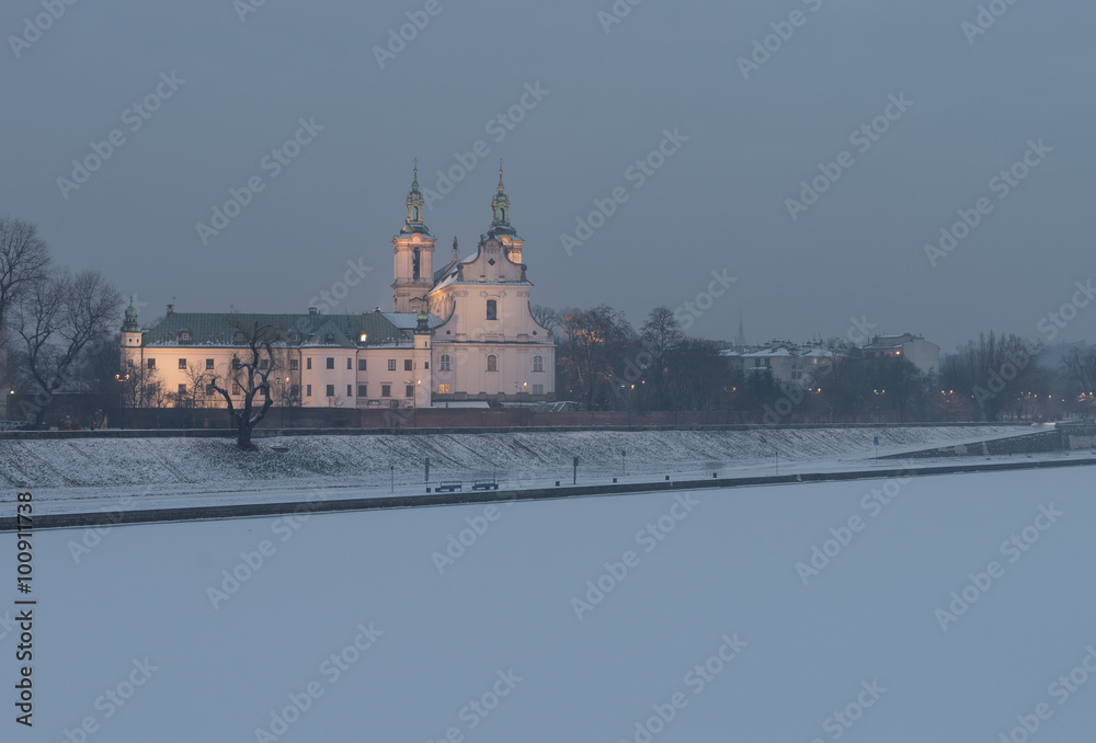 Fototapeta premium Krakow, Poland, frozen Vistula riverbank with Pauline fathers church (Skalka) in the evening