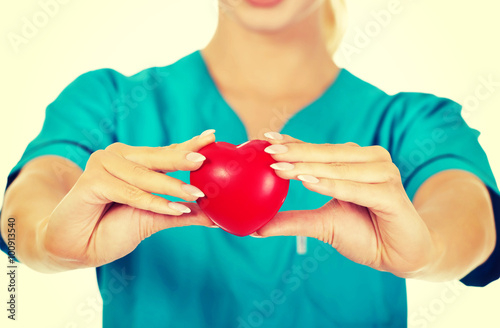 Nurse or female doctor holding red heart.