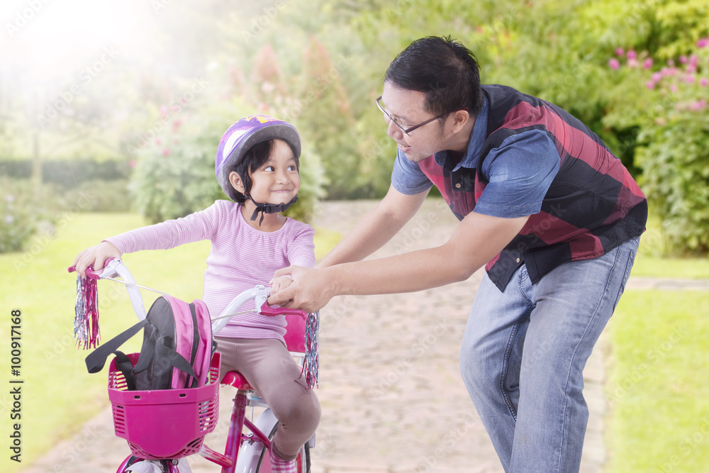 Man teach his daughter to ride bicycle
