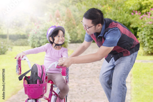 Man teach his daughter to ride bicycle