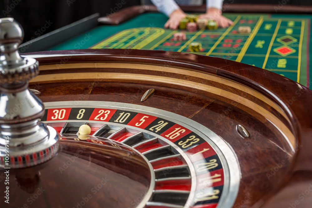 Roulette and piles of gambling chips on a green table. Roulette and piles of gambling chips on a green table.
