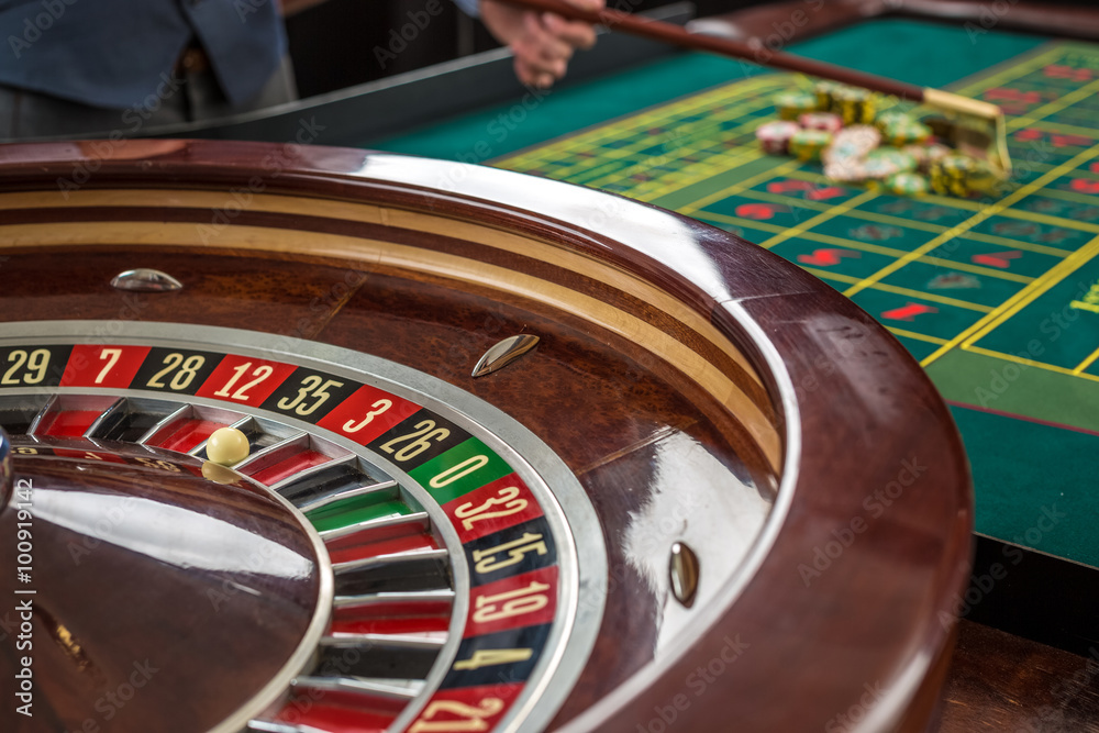 Roulette and piles of gambling chips on a green table. Roulette and piles of gambling chips on a green table.
