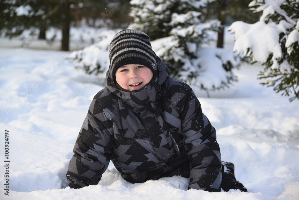 Teen boy sitting on   snow in the winter forest