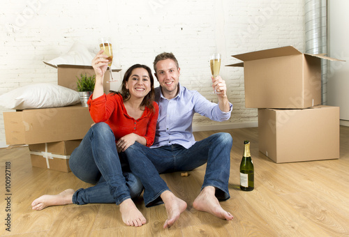 happy American couple sitting on floor unpacking together celebrating with champagne toast moving in a new house © Wordley Calvo Stock