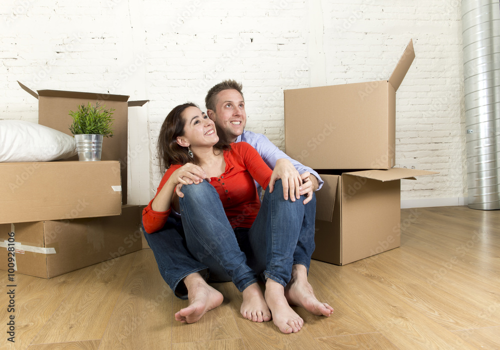 young happy couple sitting on floor together celebrating moving in new flat house or apartment