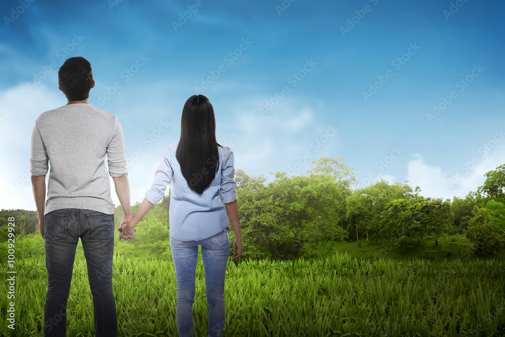 Back view of asian couple holding hand looking at the sky Back view of asian couple holding hand looking at the sky