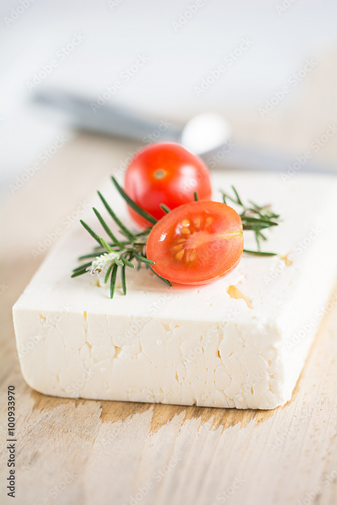 Schafskäse mit Rosmarin und Tomaten auf einem Holzbrett Schafskäse mit Rosmarin und Tomaten auf einem Holzbrett