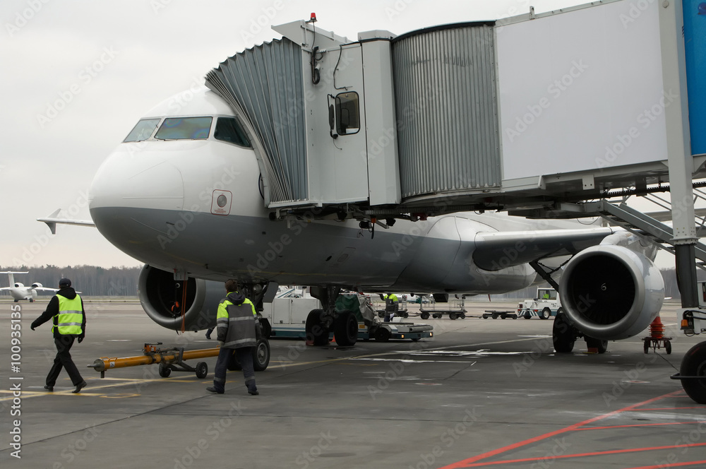Airplane docked to mobile telescopic bridge in the airport Airplane docked to mobile telescopic bridge in the airport