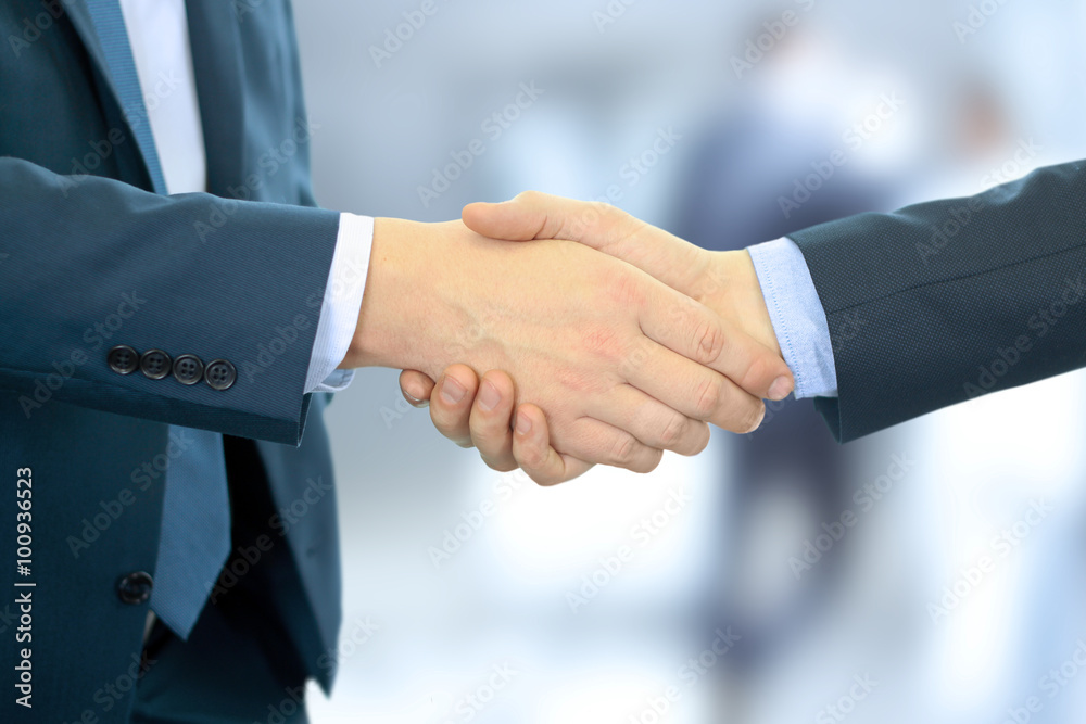 Close-up image of a firm handshake between two colleagues in office