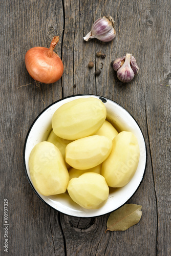 Peeled potatoes on wooden background
